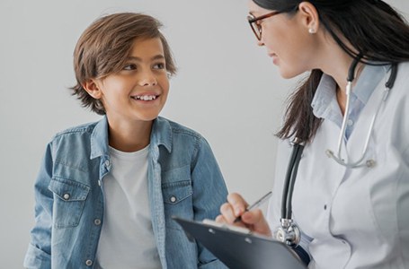 a child patient speaking and smiling with his dentist