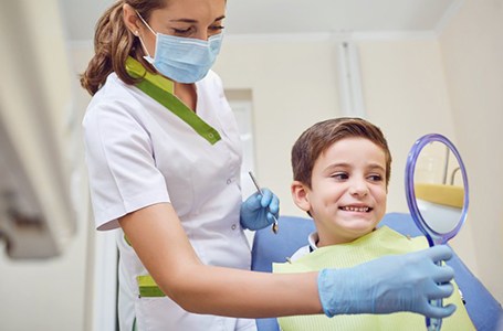 a child patient checking his smile with a mirror