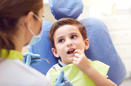 a child touching his tooth during an oral cancer screening