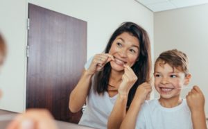 mother and young boy flossing teeth