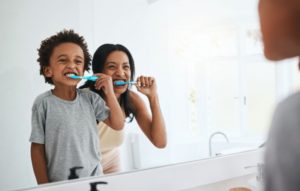 a child and mom brushing their teeth together