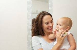 a parent brushing her infant’s teeth 